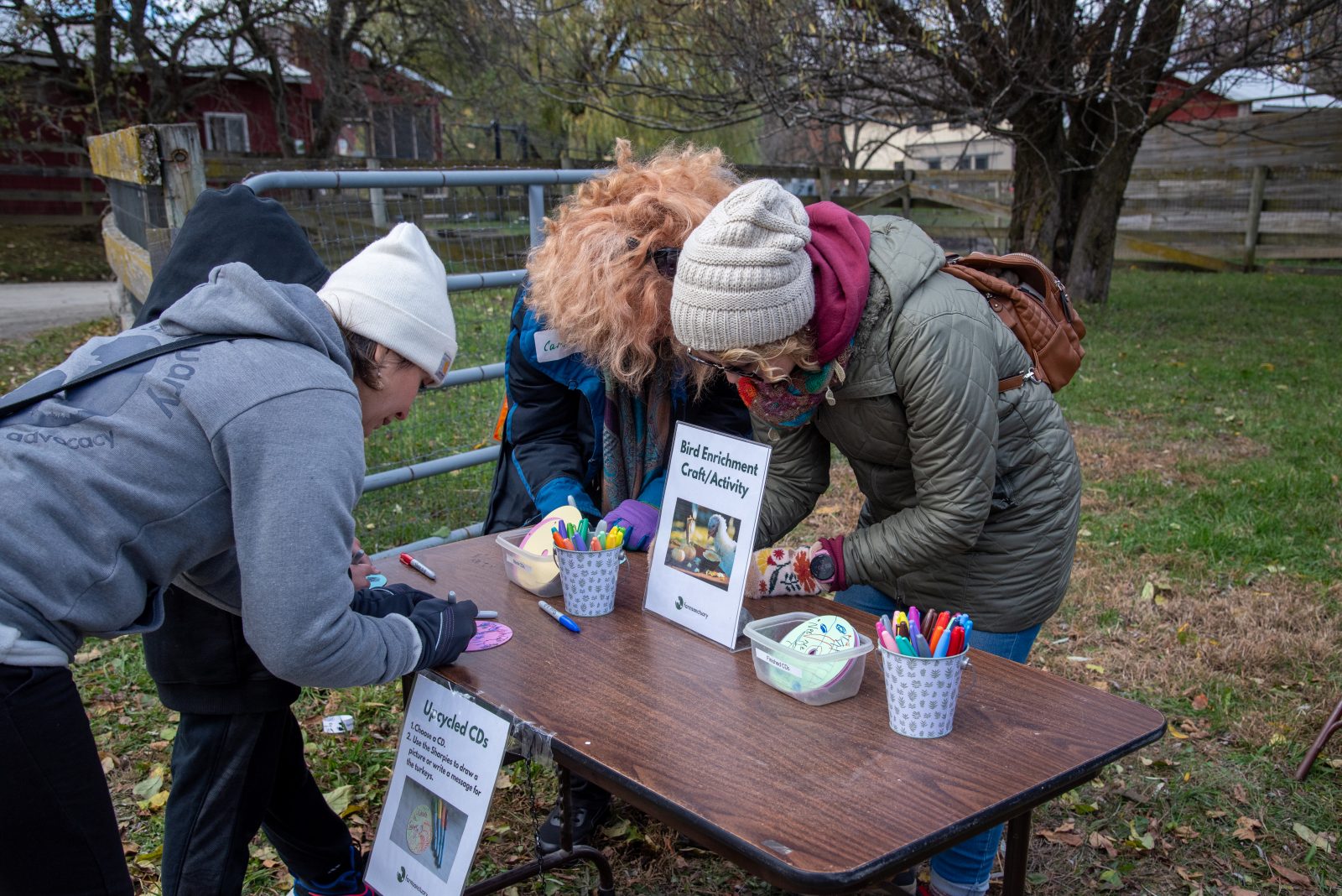 Guests at crafts table decorate enrichment activities for rescued turkeys at Farm Sanctuary