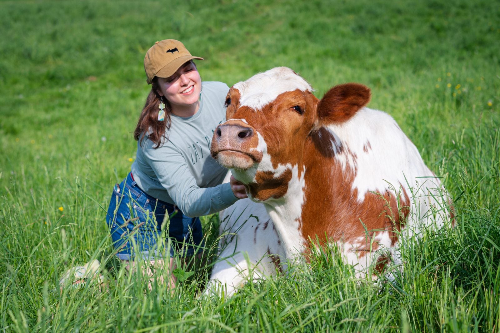 Farm Sanctuary caregiver hugs rescued steer in pasture at Farm Sanctuary NY