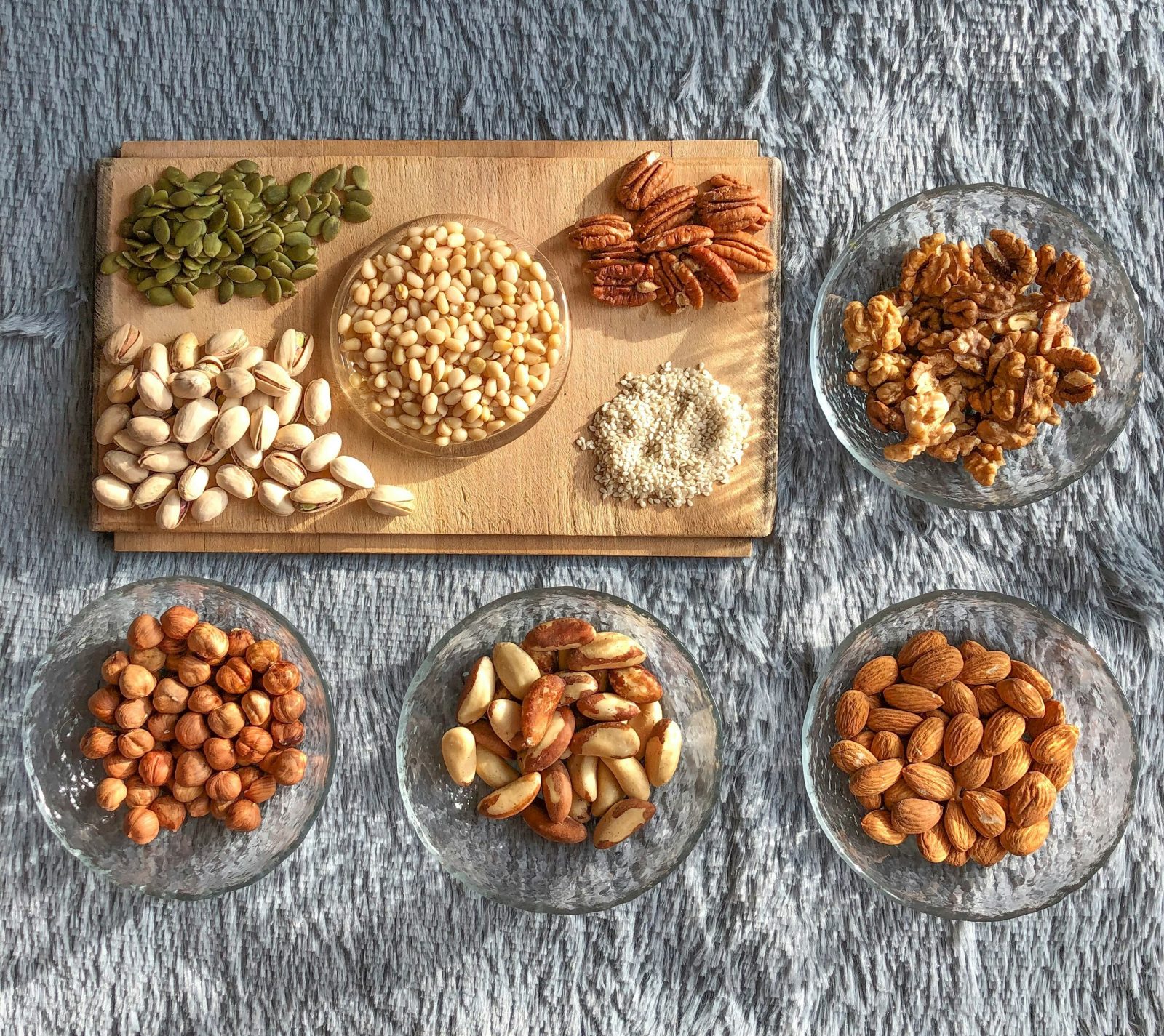Cutting board and glass bowls filled with nuts and seeds