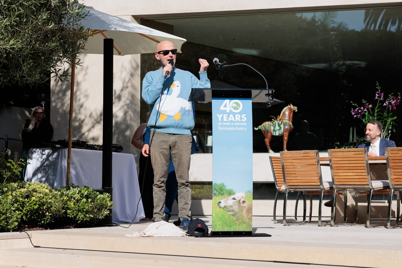 Moby speaks into microphone at podium for Farm Sanctuary's 40th anniversary