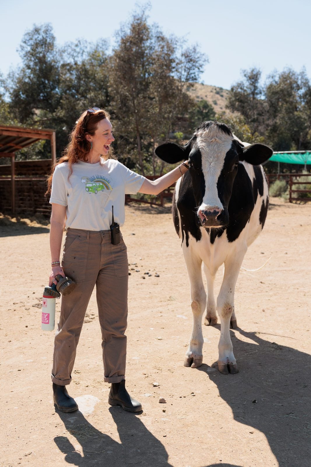 Farm Sanctuary staff Veronika smiles at rescued cow Omi, standing next to her