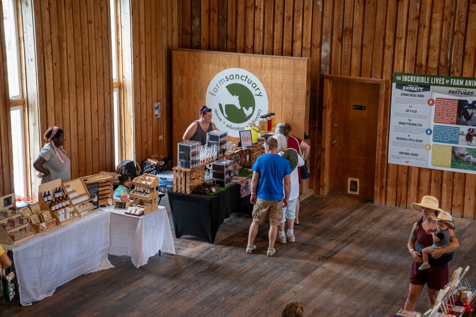 Guests visit tables hosted by local vendors at Farm Sanctuary's summer Pignic event in Watkins Glen
