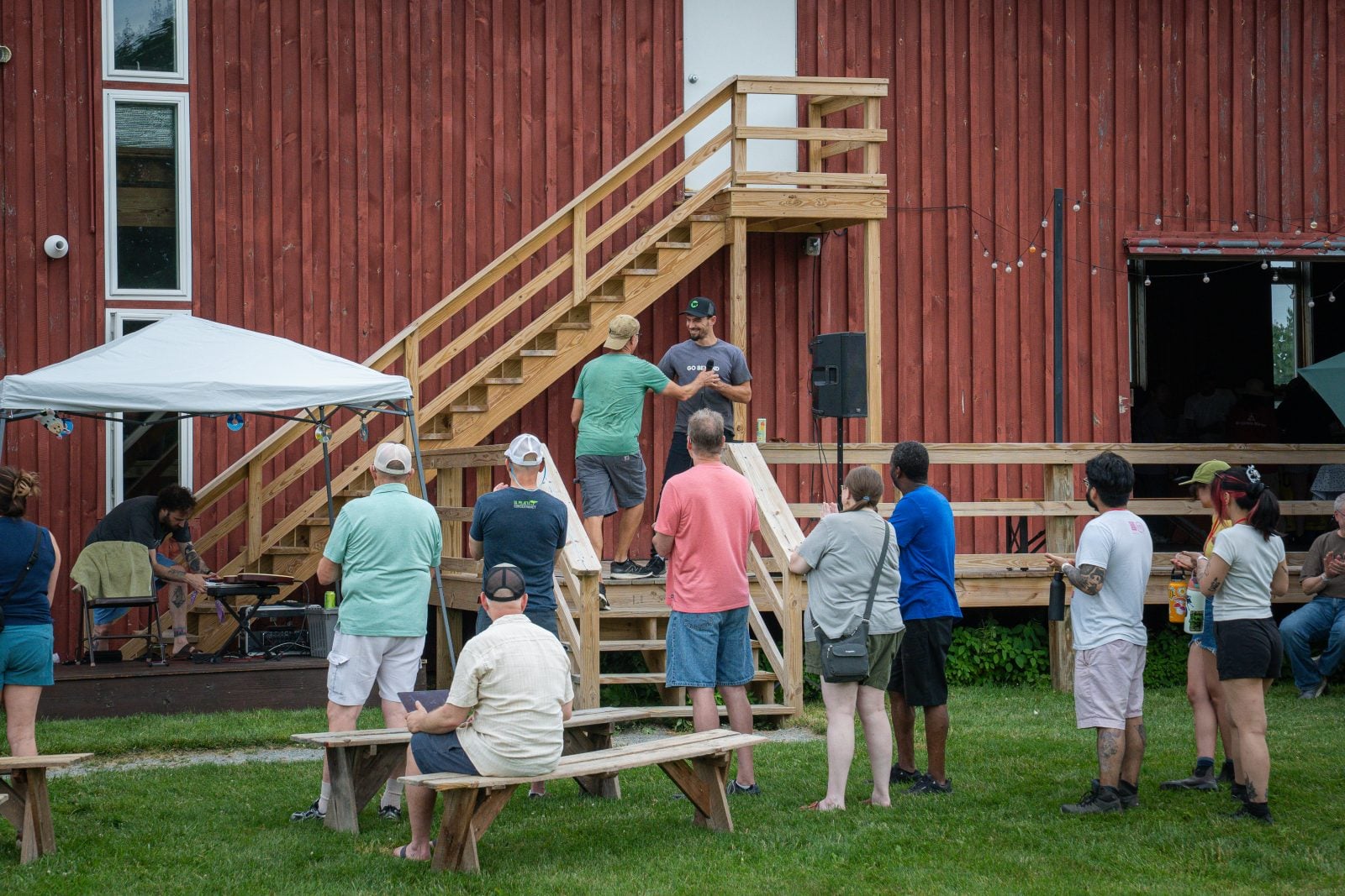 Gene Baur hands microphone to Ethan Brown, founder of Beyond, in front of guests at Farm Sanctuary's summer Pignic event