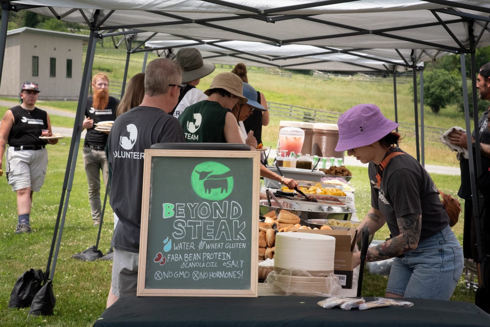 Farm Sanctuary volunteers work at a food table featuring a sign about Beyond Steak