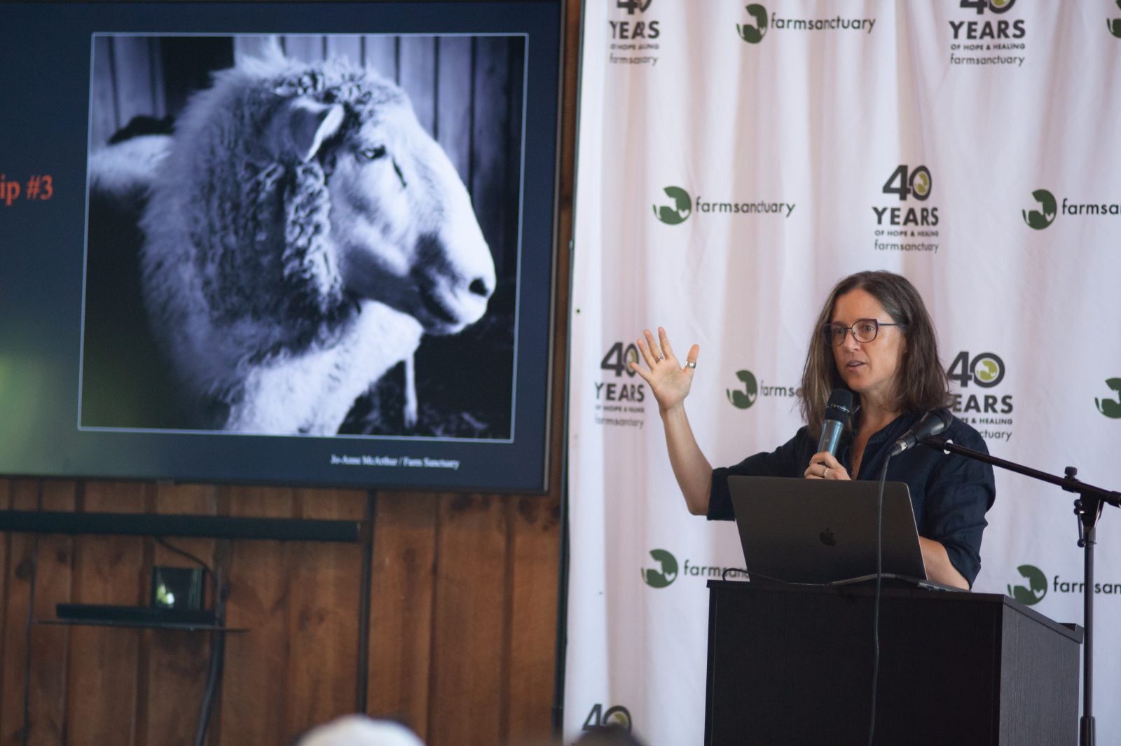 Jo-Anne McArthur gestures to a portrait of a sheep while speaking at Farm Sanctuary